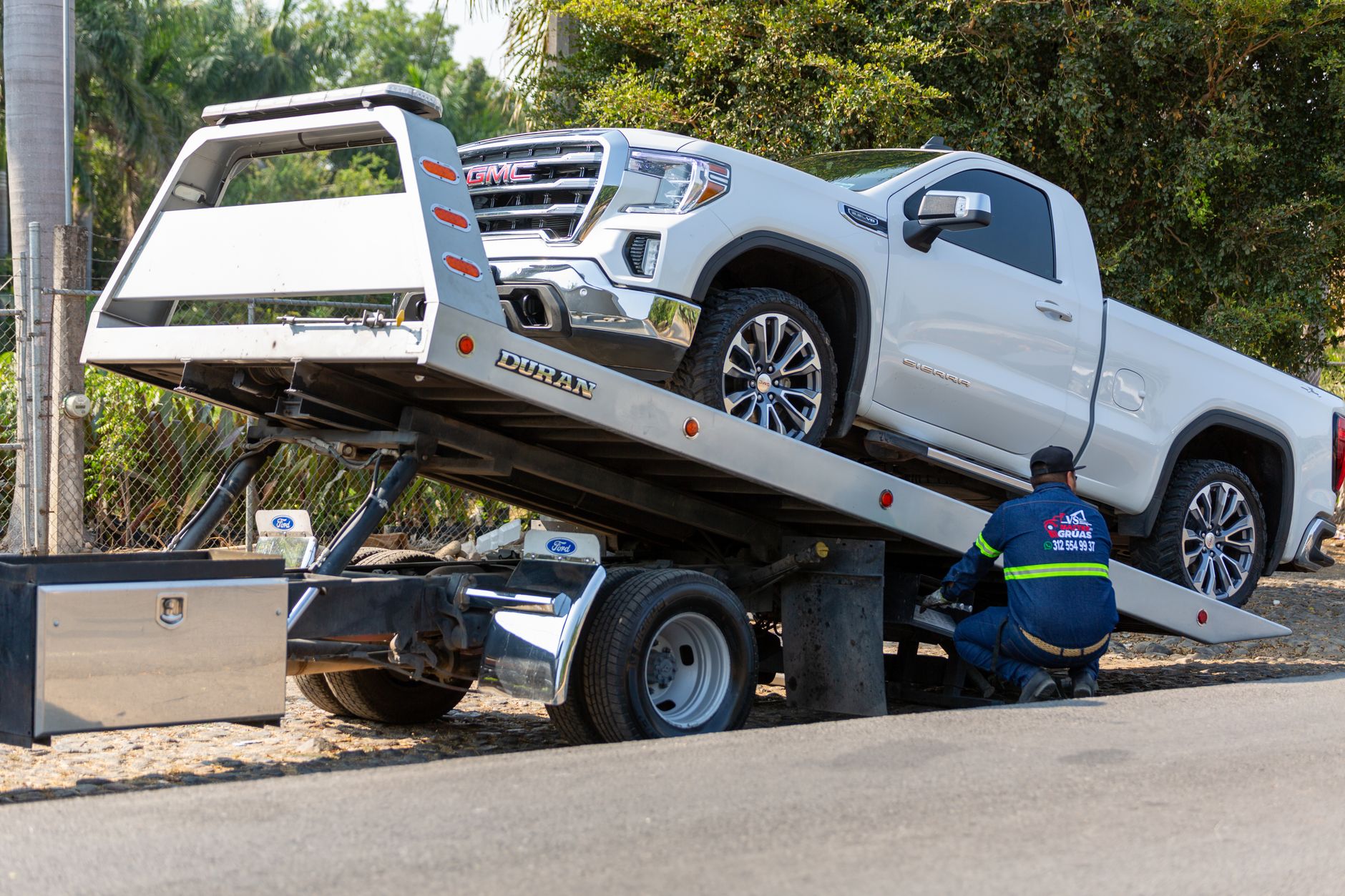 A Snappy Towing technician safely securing a vehicle onto a flatbed tow truck in a well-lit area of Altoona, Iowa at dusk.